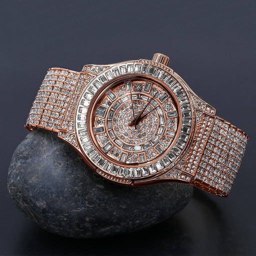 A Lilac Quartz GALLANT CZ Watch | 5110335, yellow gold plated and encrusted with shimmering CZ stones, sits elegantly on a smooth gray rock against a dark background. Its round face features intricate detailing, complemented by a stone-adorned band that exudes luxury.