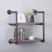 The (2 Tier - 24in) Industrial Pipe Shelving by Teal Crius, featuring high-quality galvanized steel pipes and 100% pine solid wood planks, holds a small potted plant, a picture frame, three books, and a teacup with a saucer. This two-tiered industrial floating shelf is mounted against a light gray wall.