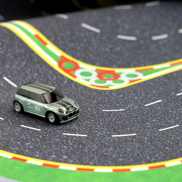 A gray toy car, adorned with racing decals, navigates winding curves on the Turbo Drift Remote Control Car Track for Big and Small Scenes by Lacatang Shop, offering a thrilling drifting experience marked by green and red borders.