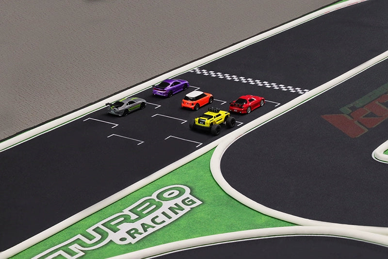 Five colorful toy cars line up on the Turbo Mini Drift Scene Remote Control Race Car Track by Lacatang Shop, featuring a black surface with white stripes and green borders labeled "Turbo Racing," ideal for exciting races.