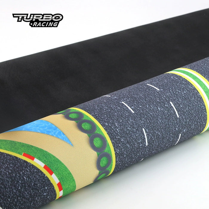 Close-up of a rolled-up Lacatang Shop's Turbo Mini Drift Scene Remote Control Race Car Track mat, featuring textured road lanes with colorful borders and the "Turbo Racing" logo in the upper left corner. The black bottom layer offers high-speed racing thrills.