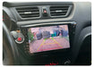 The Lacatang Shop's Develuck HD 1080P Car Rear View Camera displays a driveway with tires, a broom, and garbage bins. Parking guidelines are clear on screen, while the dashboard shows a hazard button above the display. The camera's waterproof feature maintains clarity in any weather.