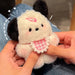 A person holds a Cute Plush Puppy Keychain by Lacatang Shop featuring black ears and a pink checkered bib with a small pink hat. Set against blue jeans and surrounded by white doodles, it's an adorable cartoon bag charm or perfect birthday gift for women and girls.