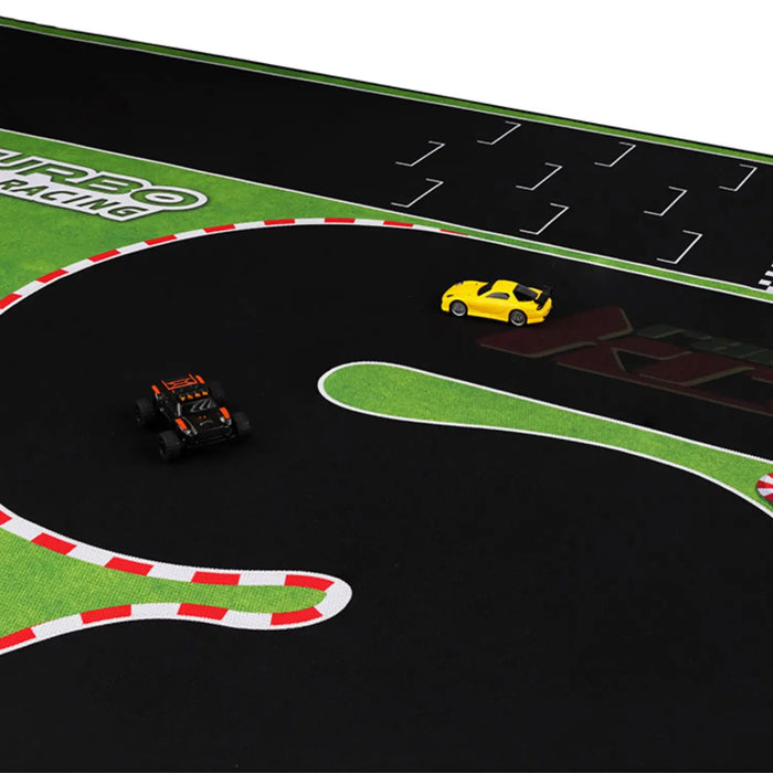 Remote control cars zoom around the vibrant TURBO RACING 1:76 track set by Lacatang Shop, featuring grass-like borders, red-and-white curbs, and sharp turns on a black surface with jump and drift features. The iconic logo enhances the racing action.