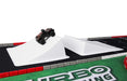 A small remote control car stands on a white ramp in the Lacatang Shop's TURBO RACING 1:76 Race Track Set, featuring green, black, and red sections with partial "Turbo Racing" visibility at the bottom.