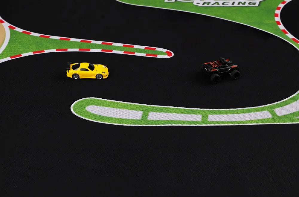 A small toy yellow car and a black monster truck sit on the Portable 1600x900mm Turbo Racing Rubber Mat by Lacatang Shop, featuring white/red striped edges and green areas, ideal for Mini RC Cars adventures with vehicles moving in the same direction.