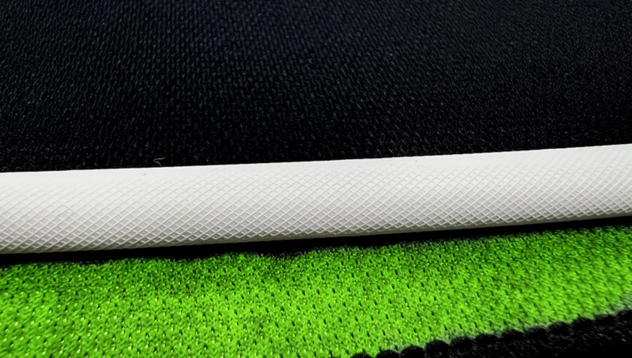 A close-up of a white cylindrical object sits on layered green and black fabric, similar to the Lacatang Shop TURBO RACING 1:76 Remote Control Car Race Track Set. The green fabric has a small circular pattern, while the black fabric showcases a larger rough texture.