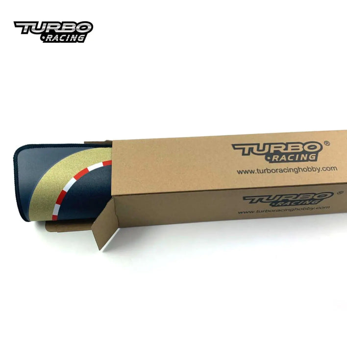 A Lacatang Shop box, open at one end, displays a rolled-up racing mat ideal for drift testing. The mat has a curved track with red and white stripes and features the TURBO RACING 1:76 Remote Control Car Track Set logo on both the box and the mat.