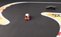 Two mini RC cars race on the Lacatang Shop's Portable Turbo Racing Rubber Mat, featuring dynamic black, red, white, and yellow sharp curves in 1:76 scale for an exciting table racing experience.