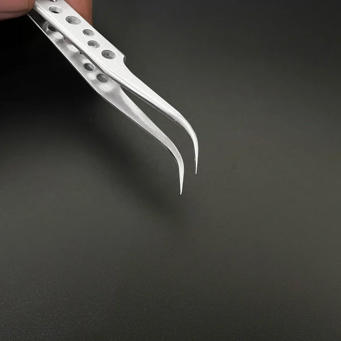 Close-up of a hand holding an AliExpress pair of Industrial Tweezers Electronics Anti-static Curved Straight Tip, featuring white, fine-tipped ends with a perforated handle against a dark background. The polished tips are sharp and slightly curved inward.