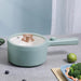 A pastel green 2024 New Portable 1.5L Multi-function Pot Rice Cooker Electric Cooking Stir Frying Noodle Pot Mini Hot Pot Household Dormitory from Lacatang Shop with a lid sits on a grey countertop. The lid features a golden knob, and the hot pot has an elongated handle. Next to it is a blue plate containing a meal of broccoli and shrimp, accompanied by a lime.