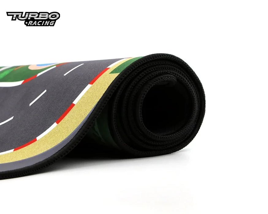 The Lacatang Shop's Portable Turbo Racing Track Mat (1600x900mm) features a curved road with green, yellow, and red details and the "Turbo Racing" logo. Ideal for mini cars (1/76, 1/64, 1/58), it has neat edges for seamless play.