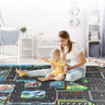 In a cozy nursery with a crib and hexagonal wall shelves, a woman smiles as her baby engages with Lacatang Shop's Colorful Cartoon City Traffic Play Mat. The vibrant educational rug features toy cars, enhances cognitive skills, and creates a cheerful ambiance.