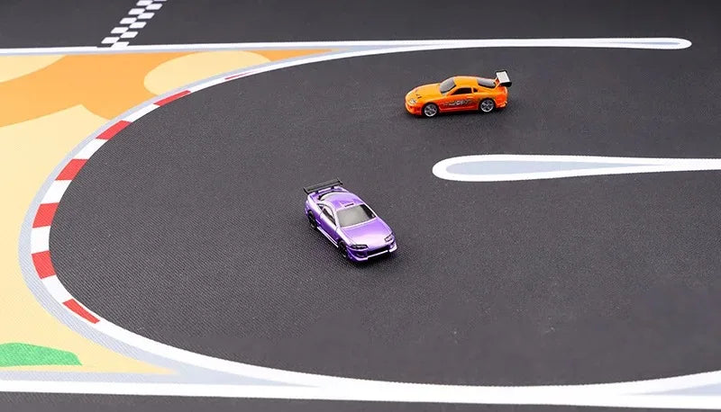 On the Lacatang Shop's Portable Turbo Racing Rubber Track Mat, a purple toy car with enhanced grip leads the curve as an orange one follows. The track's realistic white-red striped borders and checkered section add to the excitement.