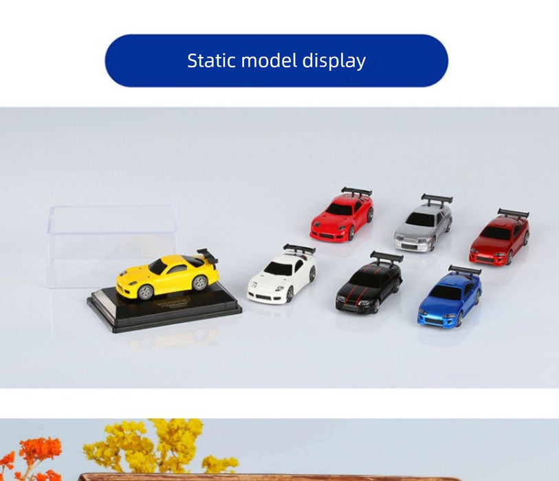 A display features seven static Turbo Racing 1:76 Miniature Full-Scale C71c72c73c74 Remote Control Electric Drift Sports Car Toys from Lacatang Shop, including a yellow car on a black pedestal. The others, resembling electric sports cars, are red, white, gray, black, and blue models arranged in a line. An empty display case is positioned to the left of the models.