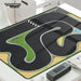 Lacatang Shop's "1:76 TURBO RACING" Drift Jump Track Mat features winding tracks, lush green areas, a checkered start/finish line, and a water feature. Accessories include cement blocks, nearby black speaker, and parts of white tables.