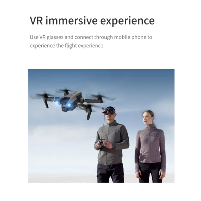 Two people, one wearing VR glasses, stand outdoors under a clear sky. The person with the glasses holds a remote control for the hovering Yellow Pandora Ninja Dragon Phantom X HD Dual Camera Smart Quadcopter Drone above. The other person stands beside them, looking at the drone. Text above reads, "VR immersive experience.