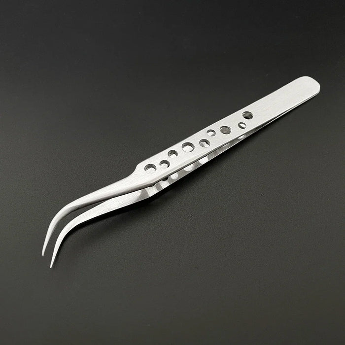 A pair of AliExpress Industrial Electronics Anti-static Tweezers with a curved tip and multiple circular holes along the handle lies on a dark surface. The design, which can be further polished to remove any black marks, enhances grip and reduces weight.