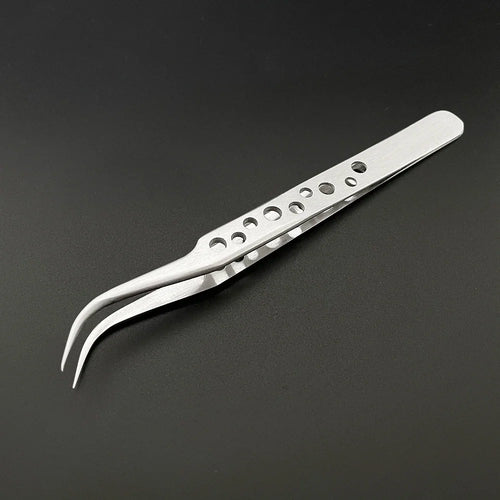 A pair of AliExpress Industrial Tweezers Electronics Anti-static Curved Straight Tip lies on a dark surface. The silver metal tweezers, featuring a pointed, curved tip and a handle designed for both grip and reduced weight, have multiple round holes. To maintain their pristine condition and remove any black marks, it’s best to regularly polish them with alcohol.