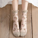 A pair of feet in Lacatang Shop's Kawaii Harajuku style Vintage Floral Lace Ruffle Socks for women, featuring pink rose patterns, a frilled top edge, and solid toe area, stand on a wooden floor, showcasing their sheer yet charming allure.