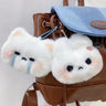 Two charming plush rabbit doll keychains, known as the Cartoon Plush Rabbit Doll Toy Keychain Sweet Cute Bag Pendant Charms from Lacatang Shop, are attached to a brown backpack with a blue flap. One rabbit has a sad expression with blue streaks under its eyes, while the other looks neutral or slightly displeased.