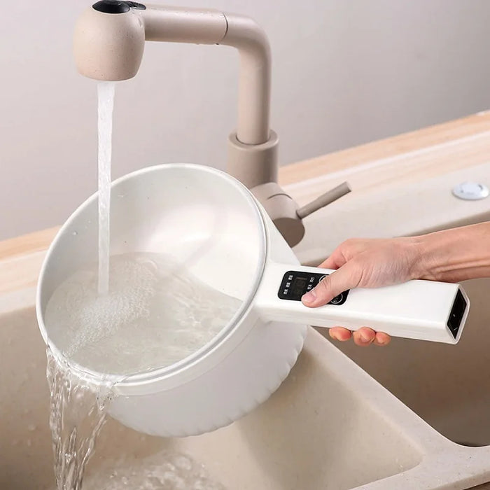 A person holds a white Lacatang Shop 1.6L Smart Electric Cooking Pot Reservation Multifunctional Non-stick Electric Wok Household Electric Hot Pot With Steamer 220V, pouring water from a faucet into a white bowl in a kitchen sink. The device seems to be controlling the flow of water. The sink and faucet are beige, and the surroundings are clean and minimalistic.