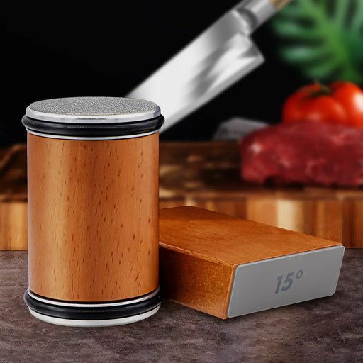 A Rolling Knife Sharpener Tool Roller Edge Countertop Knife Sharpener by AliExpress is displayed on a kitchen counter. It includes a cylindrical wooden tool and a professional-grade sharpening stone labeled with "15°." Blurred in the background are a knife, a wooden cutting board, a piece of raw meat, and some vegetables.